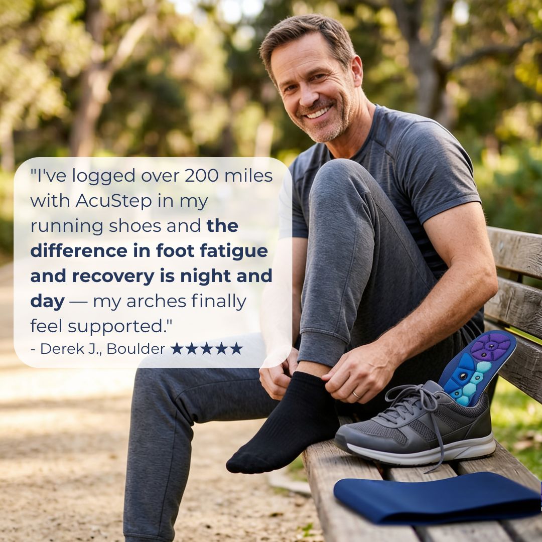 A man sitting on a wooden park bench wearing a dark gray t-shirt and gray running shoes, with one foot in a black sock while the other shoe lies beside him. A blue foot support pad is placed on the bench next to the shoe.