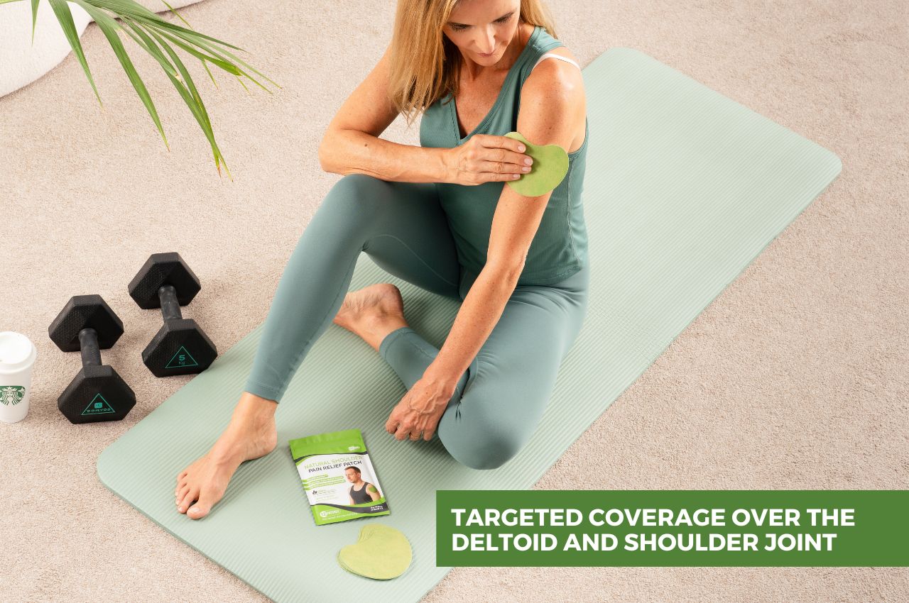 Woman sitting on a yoga mat and applying FlexiShoulder patch to her shoulder.